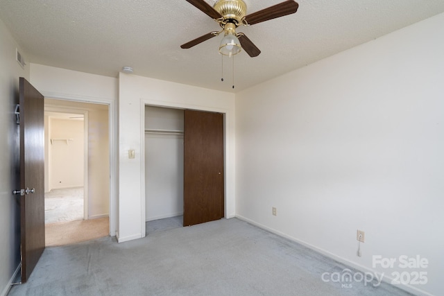 unfurnished bedroom with light carpet, a closet, a textured ceiling, ceiling fan, and visible vents