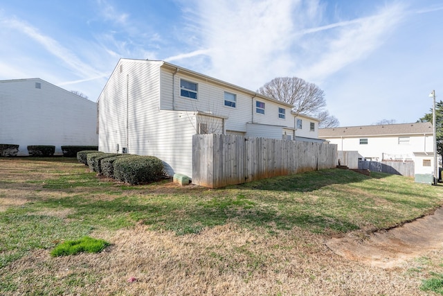 rear view of property featuring a lawn and fence