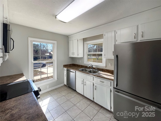 kitchen with sink, light tile patterned floors, stainless steel appliances, white cabinets, and a textured ceiling