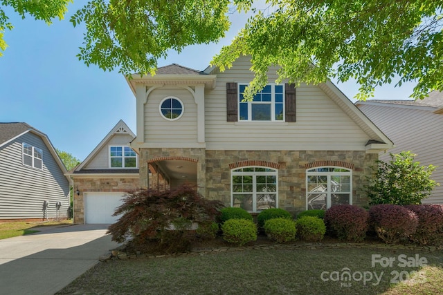 view of front facade with stone siding, an attached garage, and driveway