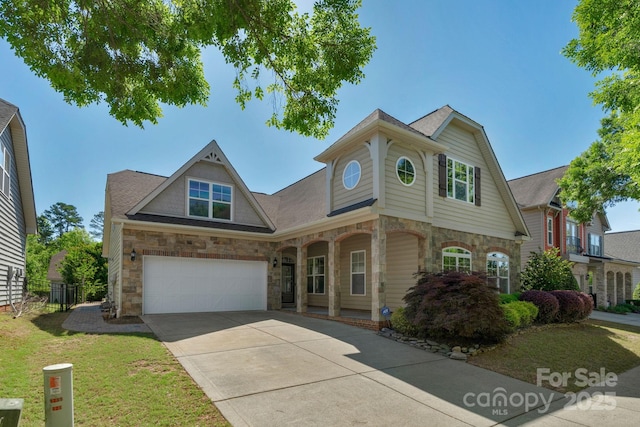 view of front of property featuring stone siding, concrete driveway, a garage, a front yard, and covered porch