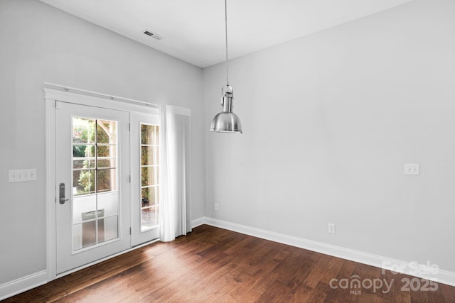 unfurnished dining area featuring dark wood finished floors and baseboards