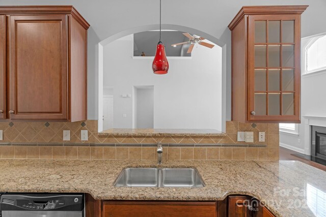 kitchen with a sink, dishwasher, arched walkways, and tasteful backsplash