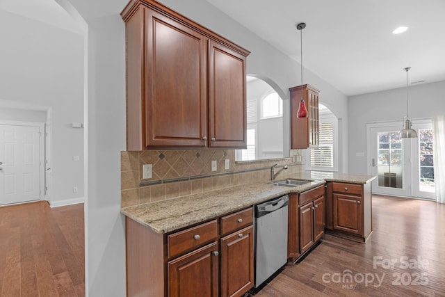 kitchen featuring stainless steel dishwasher, a sink, arched walkways, dark wood-style flooring, and recessed lighting