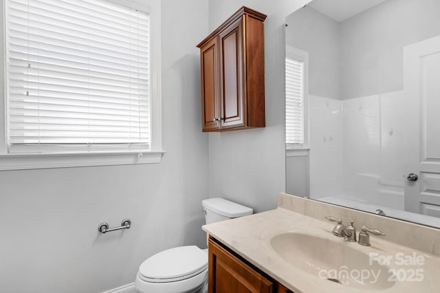 bathroom featuring toilet, vanity, and a shower