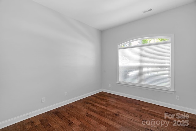 empty room featuring dark wood-type flooring and baseboards