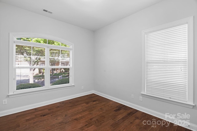 empty room with dark wood-type flooring and baseboards