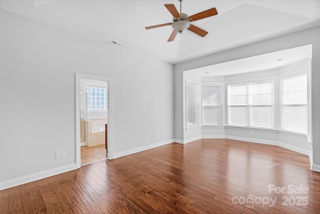 empty room featuring plenty of natural light, hardwood / wood-style flooring, ceiling fan, and baseboards