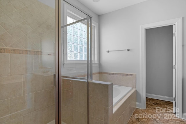 bathroom with a stall shower, a bath, tile patterned flooring, and baseboards