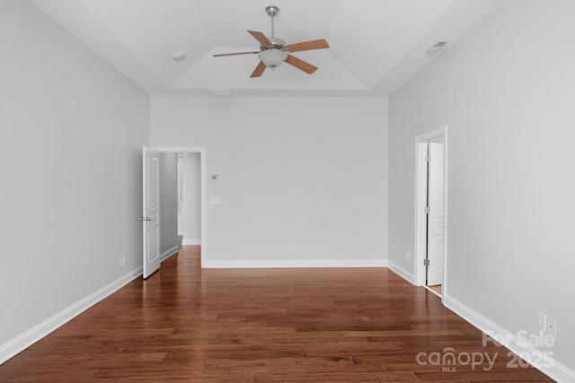 empty room featuring ceiling fan, wood finished floors, a raised ceiling, and lofted ceiling