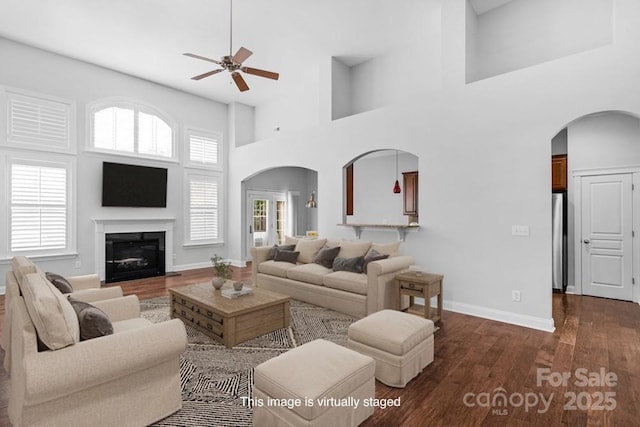 3009 Scottcrest Way, Waxhaw, NC 28173 - living area featuring arched walkways, a ceiling fan, a towering ceiling, dark wood-style flooring, and baseboards