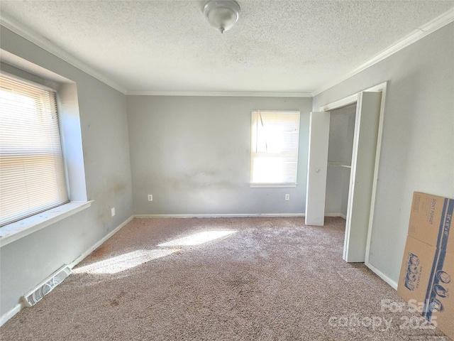 unfurnished bedroom featuring light colored carpet, ornamental molding, and a textured ceiling