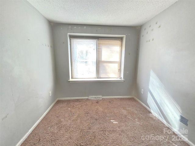 carpeted empty room with a textured ceiling