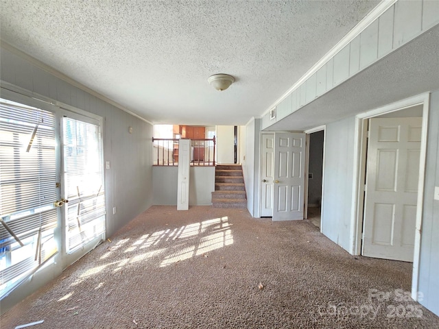 empty room featuring crown molding, carpet floors, and a textured ceiling