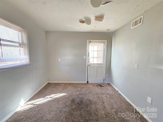 carpeted spare room featuring ceiling fan and a textured ceiling