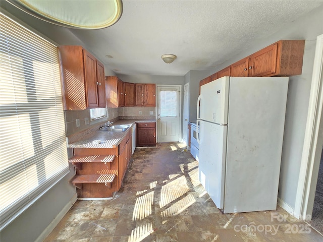 kitchen featuring tasteful backsplash, sink, white appliances, and a textured ceiling