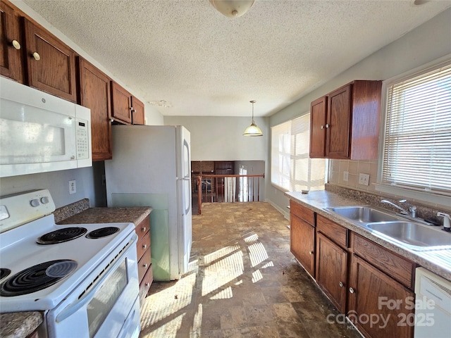 kitchen featuring hanging light fixtures, sink, a textured ceiling, and white appliances