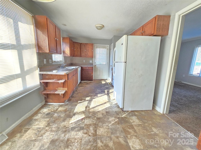 kitchen with white refrigerator, sink, and backsplash