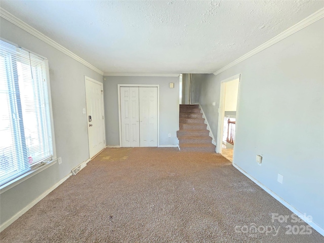 unfurnished room with ornamental molding, carpet flooring, and a textured ceiling