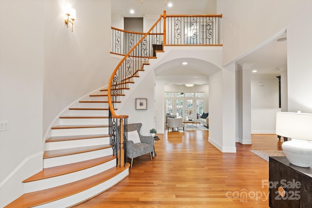 entryway featuring a towering ceiling, stairway, baseboards, and wood finished floors