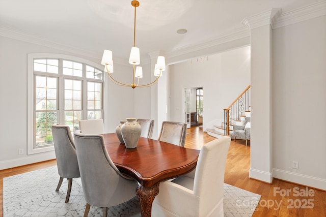 dining area with a notable chandelier, crown molding, stairway, and light wood finished floors