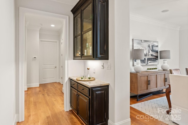 bar featuring baseboards, light wood finished floors, and crown molding