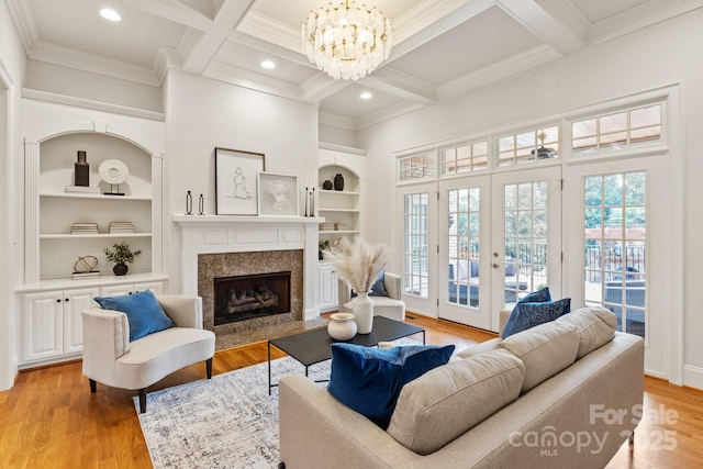 living area featuring light wood-style flooring, beamed ceiling, and a high end fireplace