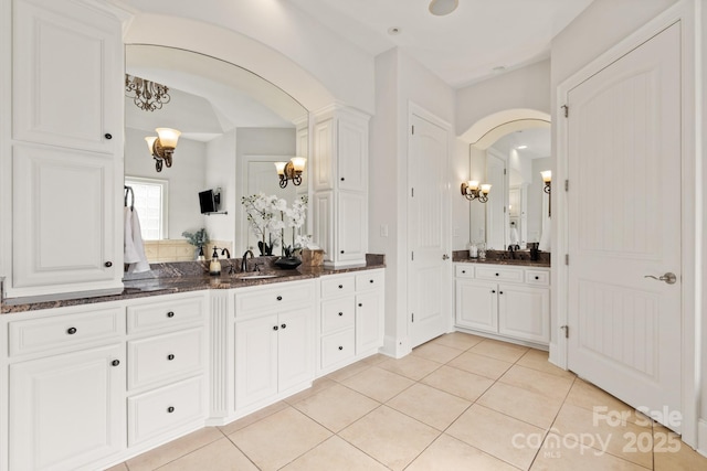 full bathroom with a chandelier, vanity, and tile patterned floors