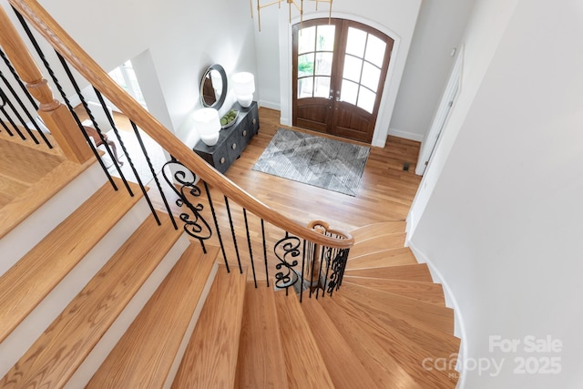 foyer featuring stairs, baseboards, wood finished floors, and french doors