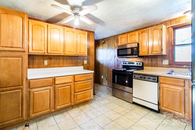 kitchen featuring light countertops, appliances with stainless steel finishes, a sink, and wooden walls