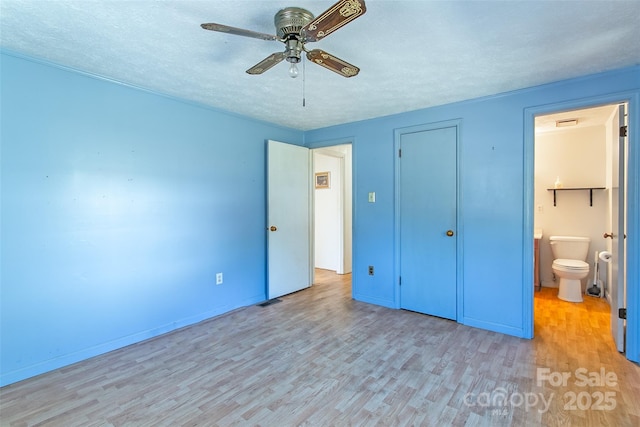 unfurnished bedroom with a closet, light wood-style flooring, a textured ceiling, and ensuite bathroom