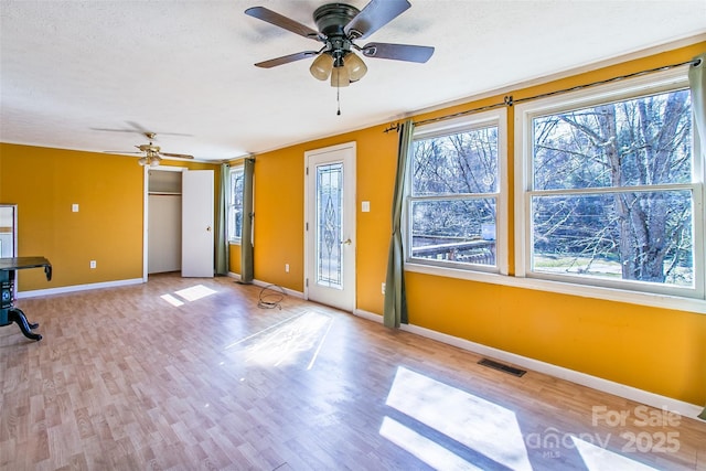 interior space with a textured ceiling, light wood-style flooring, and baseboards