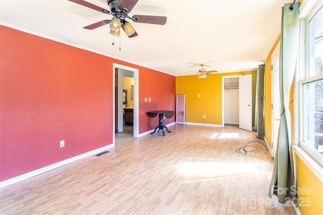 empty room with light wood finished floors, ceiling fan, baseboards, and a wealth of natural light