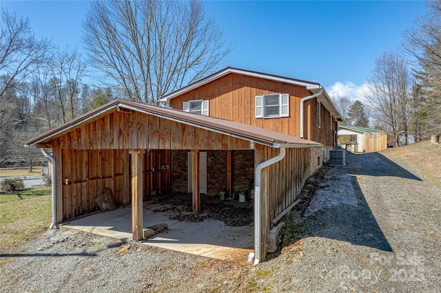 view of side of home with driveway, a garage, and cooling unit