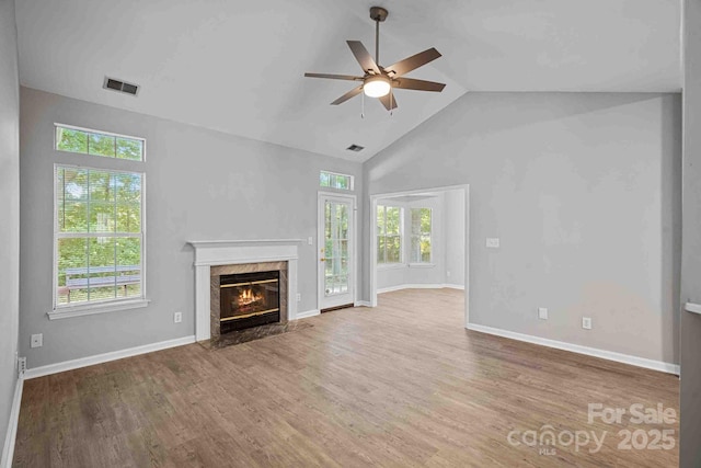 unfurnished living room featuring ceiling fan, wood-type flooring, a premium fireplace, and high vaulted ceiling