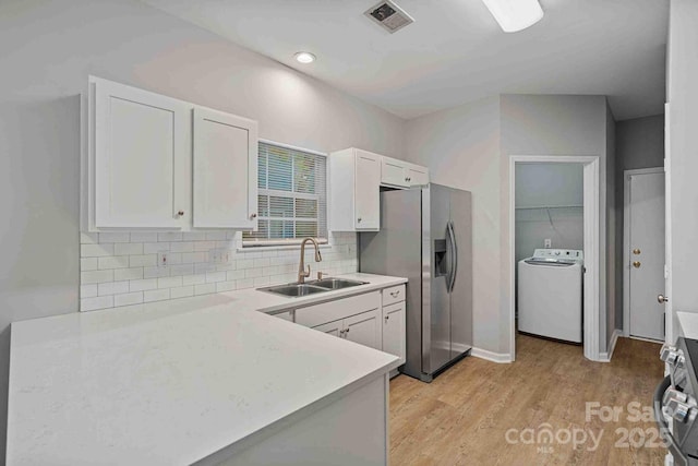 kitchen with sink, white cabinetry, stainless steel appliances, light hardwood / wood-style floors, and washer / clothes dryer