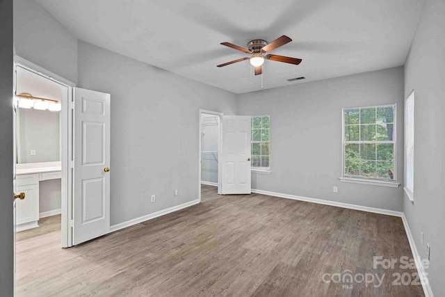 unfurnished bedroom with a spacious closet, a closet, ceiling fan, and light wood-type flooring