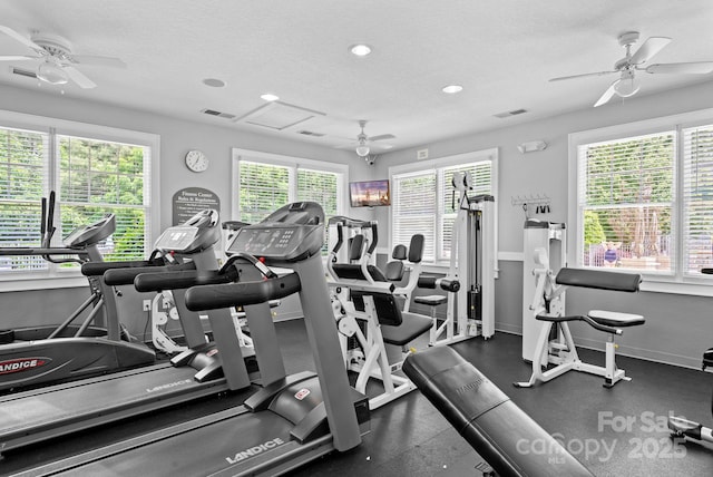 gym featuring a healthy amount of sunlight, ceiling fan, and a textured ceiling