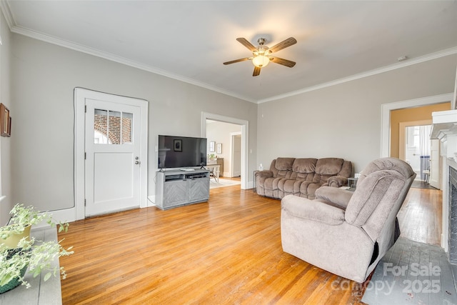 living room with hardwood / wood-style flooring, ceiling fan, and crown molding