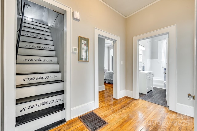 hallway with crown molding and light hardwood / wood-style floors
