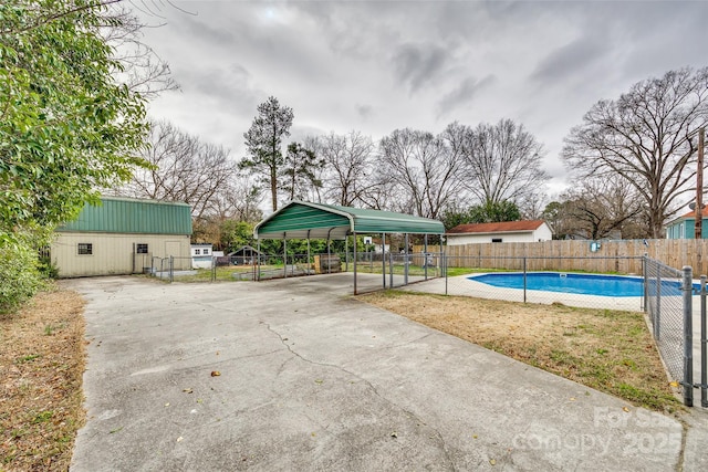 view of pool with a carport and an outbuilding