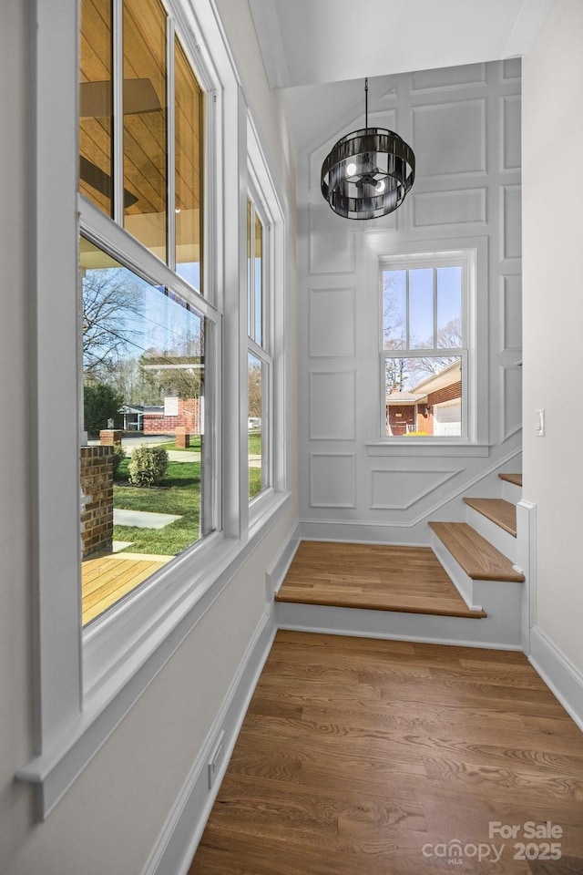 details featuring an inviting chandelier, a decorative wall, wood finished floors, and baseboards