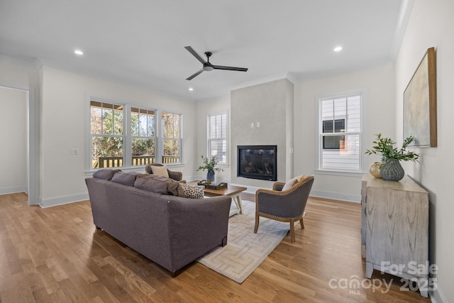 living room with a healthy amount of sunlight, a glass covered fireplace, and light wood finished floors