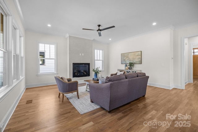 living room with visible vents, ornamental molding, wood finished floors, a fireplace, and baseboards