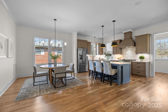 dining area featuring baseboards, visible vents, light wood-style floors, crown molding, and a notable chandelier