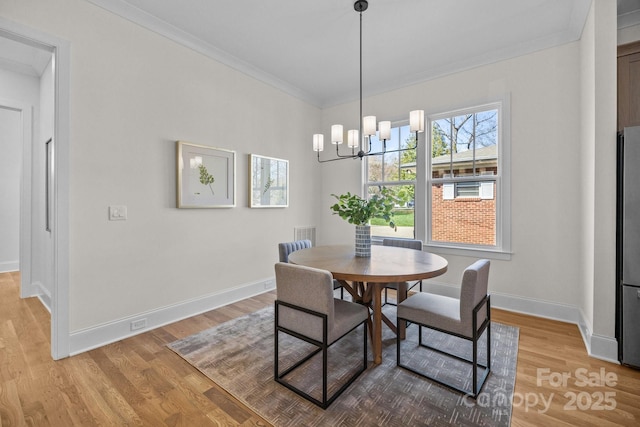 dining area with a chandelier, light wood-type flooring, baseboards, and ornamental molding