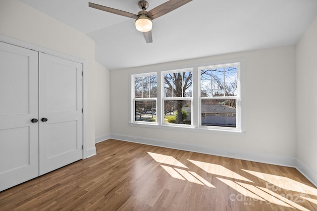 unfurnished bedroom with ceiling fan, wood finished floors, a closet, and baseboards