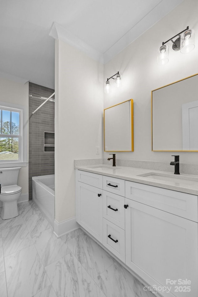 full bath with double vanity, marble finish floor, toilet, and a sink