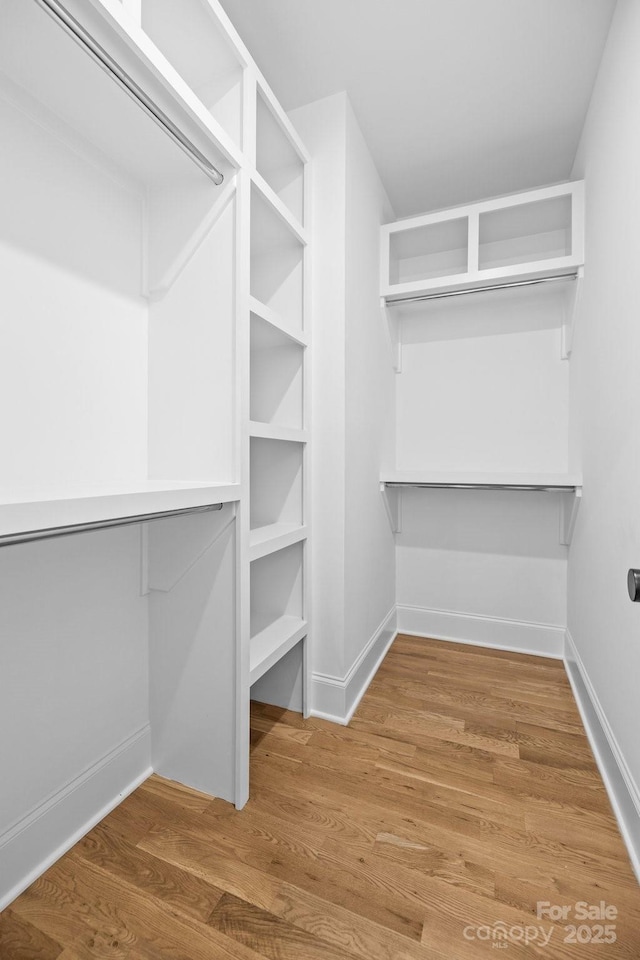 walk in closet with wood finished floors