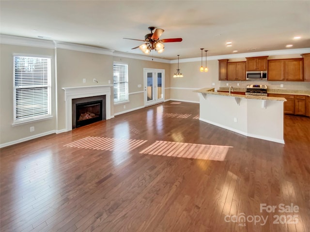 unfurnished living room with crown molding, dark hardwood / wood-style floors, sink, and ceiling fan